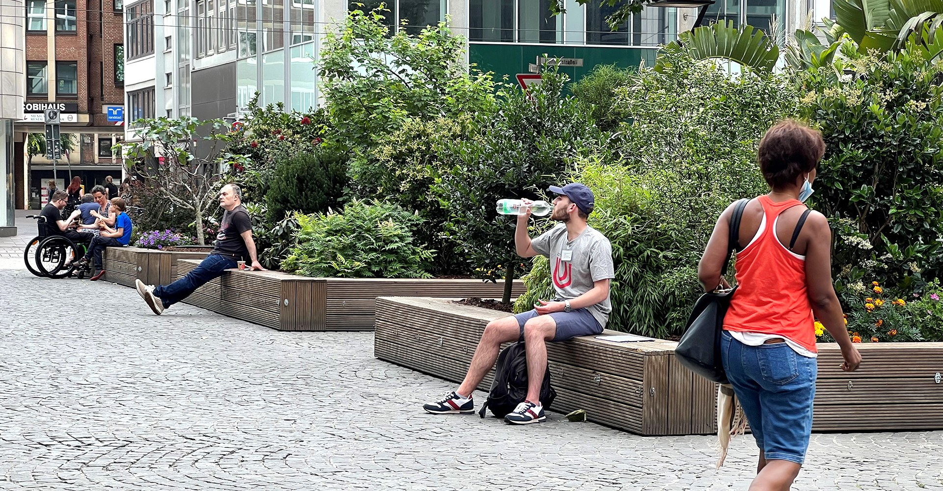 Mehrere Personen sitzen vor grünen Flächen in der Bremer Innenstadt